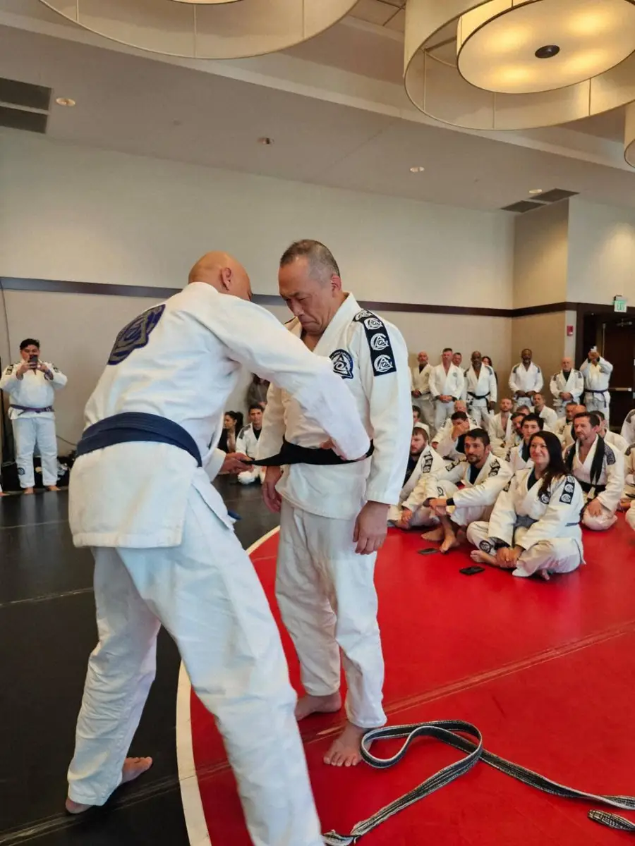 ホイス・グレーシー（左）から黒帯を授与され感極まるMAX増澤氏