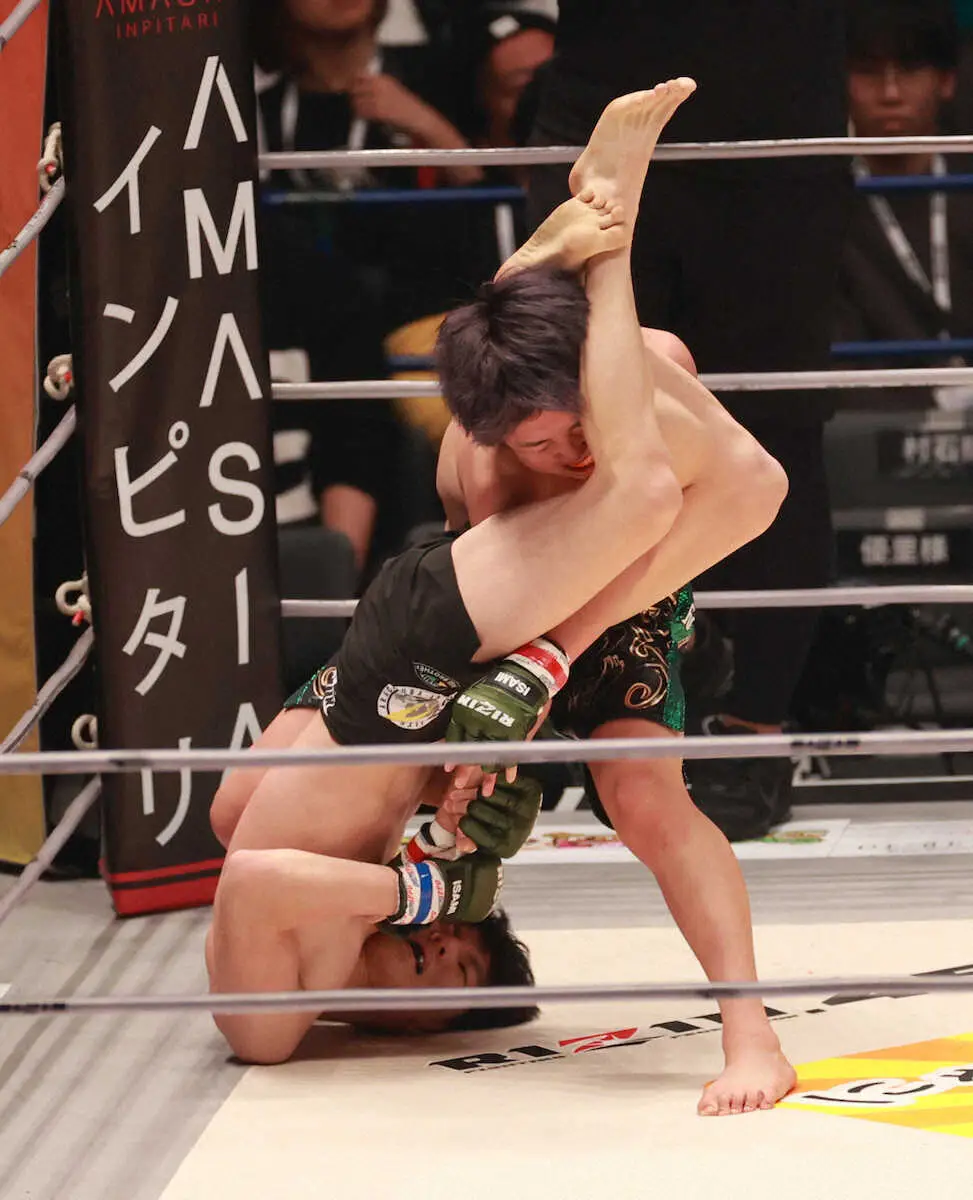 兄・天心のデビュー戦に酷似！1R、シン（左）の関節技に苦戦する那須川（撮影・篠原岳夫）