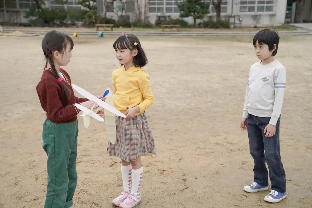 連続テレビ小説「舞いあがれ！」第14話。小学校・校庭にて。飛行機を持って校庭に集まる岩倉舞（浅田芭路）たち（C）NHK