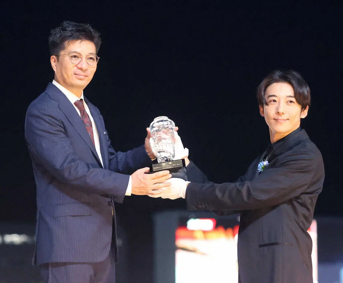 プレゼンターの高橋一生（右）からトロフィーを贈られる藤田オーナー　